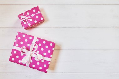 İki güzel, pembe lekeli beyaz kurdele yılbaşı, Sevgililer günü, Doğum günü veya anneler günü tebrik için kutuları hediye. El yapımı hediye kutuları beyaz vintage ahşap zemin üzerinde. Kopya alanı ile üstten görünüm.