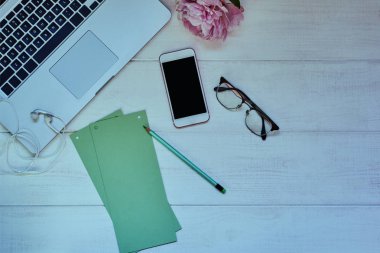 Kadın masaüstü çeşitli nesnelerle. Dizüstü bilgisayar, fincan kahve, smartphone ve boş kağıt ofis masası üzerinde yalan. Yaratıcı kişinin çalışma alanı. Üstten görünüm Resepsiyon gadget'lar ile kopya alanı ile sahte.