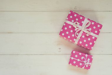 İki güzel, pembe lekeli beyaz kurdele yılbaşı, Sevgililer günü, Doğum günü veya anneler günü tebrik için kutuları hediye. El yapımı hediye kutuları beyaz vintage ahşap zemin üzerinde. Kopya alanı ile üstten görünüm.