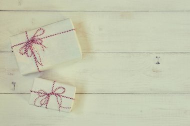 Eski püskü ahşap arka plan üzerinde Vintage hediye kutuları. Hediye kutusu beyaz kağıt sarılı, kırmızı ve beyaz baker sicim etiketi ile bağlı. Vintage tarzı. Tasarımınız için arka plan. Tatil ambalaj kavram.