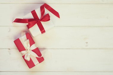 Tatil arka plan beyaz ve kırmızı hediye kutuları pastel antika arka plan üzerinde saten kurdele ile. Sahte hediye kutuları ve ve dekoratif kurdele ve yay. Düz yatıyordu, en iyi görünümü fotoğraf kadar sahte.
