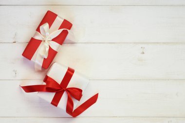 Tatil arka plan beyaz ve kırmızı hediye kutuları pastel antika arka plan üzerinde saten kurdele ile. Sahte hediye kutuları ve ve dekoratif kurdele ve yay. Düz yatıyordu, en iyi görünümü fotoğraf kadar sahte.