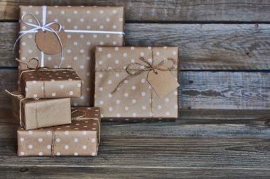 Hediye kutuları sicim ve etiket için metin ile beyaz kurdele ile Noel, Sevgililer, Doğum günü veya anneler günü için vintage ahşap arka plan üzerinde bağlı kraft kağıt sarılı. Tatil kavramı. Seçici odak.