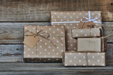 Hediye kutuları sicim ve etiket için metin ile beyaz kurdele ile Noel, Sevgililer, Doğum günü veya anneler günü için vintage ahşap arka plan üzerinde bağlı kraft kağıt sarılı. Tatil kavramı. Seçici odak.