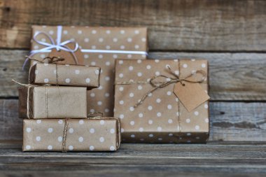 Hediye kutuları sicim ve etiket için metin ile beyaz kurdele ile Noel, Sevgililer, Doğum günü veya anneler günü için vintage ahşap arka plan üzerinde bağlı kraft kağıt sarılı. Tatil kavramı. Seçici odak.