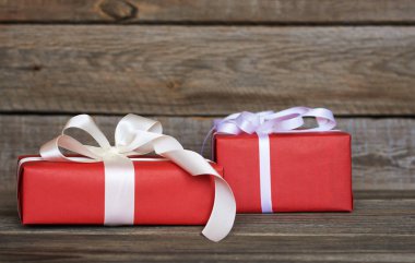 Kırmızı hediye kutusu beyaz kurdele ve ahşap duvar arka plan kopya alanı ile yay ile sarılmış. Yılbaşı, Sevgililer günü, Doğum günü veya anneler günü tebrik için sunar. Tatil ambalaj kavram.