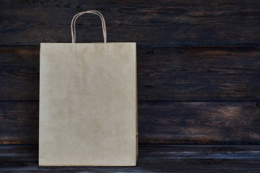 Mock-up kahverengi craft kağıt paket kulplu, boş alışveriş çantası için logo veya tasarım, ahşap tahta arka plan, gıda dağıtım, satış, tüketim ve reklam kavramı bulunduðu.