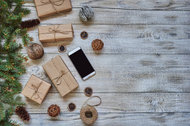 Cep telefonu kırmızı kurdele ve herdem yeşil çam dalları Beyaz ahşap zemin üzerinde hediye kutusu.