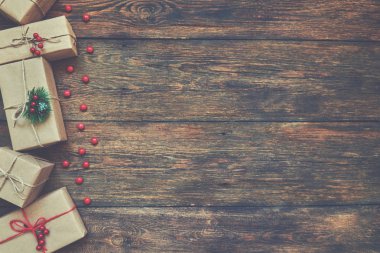 Noel hediye kutusu ile kraft kağıt sarılı ve ahşap bir masa üzerinde kırmızı ve beyaz sicim ile bağlı. Vintage tarzı.