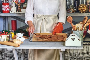 Noel için zencefilli kurabiye yapma kadın. Damlama pan ile pişmiş çerezleri, mutfakta tutan kadın pudra.