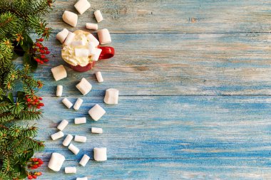 Üstten görünüm kırmızı fincan sıcak çikolata ve şekerleme. Eski ahşap arka plan üzerinde kırmızı meyveler ile köknar ağacı dalı. Noel arka plan.