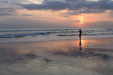 Tropik sahilde yürüyüş ve gün batımını izlemek genç güzel kız silüeti. Yaz plaj tatil insanlar. Gökyüzü ve deniz. Güzel yaz gün batımı. Özgürlük kavramı. Arka plan