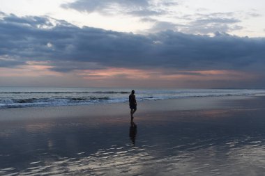 Bir başka üzerinde yürüyen bir yalnız adam siluet Plajı ıssız. Günbatımı içinde belgili tanımlık geçmiş. Sağlıklı yaşam, insanlar yaz plaj tatil