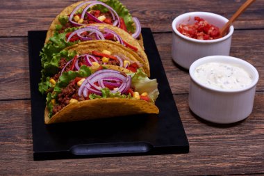 Tavuk eti, kırmızı domates ve lezzetli salsa ve ekşi krema sos ile Mor Soğan kesme parçaları ile ulusal baharatlı yemek closeup görüntü