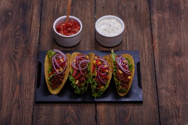 Lezzetli Meksika tacos kırmızı domates, mor soğan, yeşil salata, Mısır ve kıyma cips içinde. Beyaz ekşi krema ve geleneksel yemek için kırmızı salsa sos          