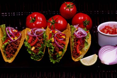 Portre resim ile Meksika Ulusal fiş kıyma, marul, Mısır, hasır tabl üzerinde yalan kalori akşam yemeği için mor soğan