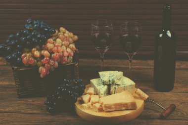 Olgun renkli üzüm sepeti ayakta plakalı yanındaki masada sağlıklı lifestyl için lezzetli rokfor taşlarla düzenlenmiş demet