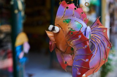 Renkli Hatıra arka plan. Asılı dekorasyon içinde belgili tanımlık çarşı. El yapımı metal balık turist piyasada asılı. Hatıra Eşyası satışı. Desenli komik el yapımı balıklarla parlak renkli.