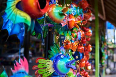 Renkli Hatıra arka plan. Asılı dekorasyon içinde belgili tanımlık çarşı. El yapımı metal balık turist piyasada asılı. Hatıra Eşyası satışı. Desenli komik el yapımı balıklarla parlak renkli.