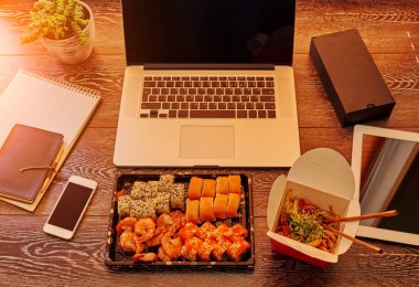 Başı işleri, defter, kalem, smartphone ile işyeri. İş - ofis zaman eksikliği, Hızlı öğle yemeği. Erişte ve suşi dizüstü yanında masaüstünde ayarla. Çalışma ve yaşam tarzı arka plan