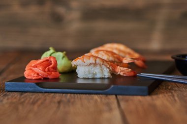 Kaplan karides, wasabi ve ahşap masanın üzerinde yatan pembe zencefil taze nigiri suşi.