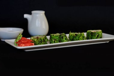 Suşi rulo suşi karides, avokado, krem peynir, susam ile. Japon yemekleri. Sağlıklı kale ve avokado suşi yemek çubukları ile rulo. Suşi koyu arka plan üzerinde. Set ile karides, wasabi ve zencefil. 