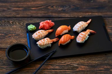 Yemek suşi arka plan. Sashimi suşi yemek çubukları ve soya ile kapatın. Japon gıda Restoran, sushi koyu arka plan üzerinde. Taze somon, karides, wasabi ve zencefil ile ayarla suşi yapılan.