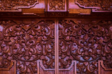 Geleneksel Bali tarzı kapı oyma. Çiçek desenli tasvir vinyet etkisi ile kırmızı bir kapı detayını. El yapımı antika ahşap oyma kapı. Muhteşem ve süslü giriş kapısı Tapınağı.
