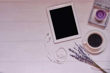 Fincan sade kahve, boş ekran, mum, taze çerez ve çiçeklerle beyaz vintage arka planda dijital tablet ile çalışma alanı. Kablosuz iletişim kavramı. Üstten görünüm, düz yatıyordu, kopya alanı.