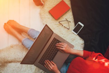 Üstten görünüm evde otururken dizüstü bilgisayar onun kucağına tutan genç bir kadın. Internet mağaza tarama için dizüstü bilgisayar kullanan kadın. Online alışveriş kavramı. Evde halı üzerinde oturan genç kadın.