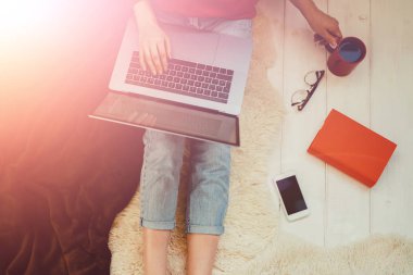 Evde otururken dizüstü bilgisayar onun kucağına tutan genç kadın. Internet mağaza tarama için dizüstü bilgisayar kullanan kadın. Online alışveriş kavramı. Evde halı üzerinde oturan genç kadın.