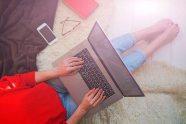 Evde otururken dizüstü bilgisayar onun kucağına tutan genç kadın. Internet mağaza tarama için dizüstü bilgisayar kullanan kadın. Online alışveriş kavramı. Evde halı üzerinde oturan genç kadın.