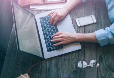 Öğrenci, Genç kadın veya kız kıyafeti. İn gerekli modern genç kişi için ek yükü. Farklı nesneleri ofis masasında. Gözlük, akıllı telefon, laptop. Eller üstünde laptop kapatın. Seçici odak.