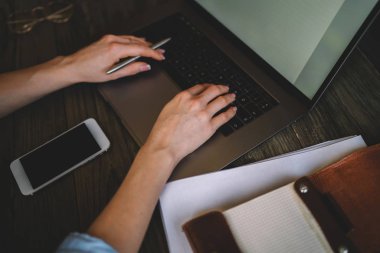 Çalışma ve ahşap masa üstünde laptop klavye üzerinde tipik bir iş kadının elleri closeup görüntüsü. Evde ofiste onun masasında dizüstü bilgisayar mesai kullanarak office çalışan kadın.