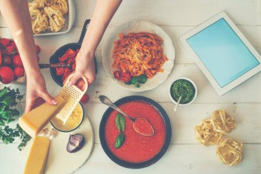 Mutfağında yemek için bir tablet bilgisayar kullanan genç kadın. Sağlıklı yemek. Kadın ev hanımı bir tarifi mutfakta bir tablet bilgisayar ile internetten yemek pişiriyor. Yumuşak odak.