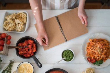 Tarif kitabı kadının bir tablo önünde elinde mutfak eşyaları ve taze sebze ile açıldı. Bir yemek kitabı talimatları sırasında yemek bir ev kadını. Senin metin için yer. Sağlıklı gıda.