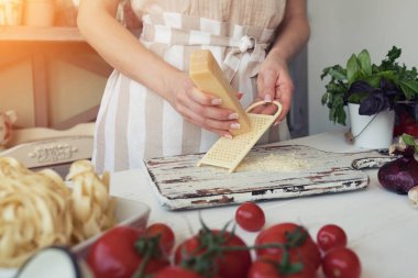 Domates, peynir ve diğer malzemelerin mutfak tezgahının üzerine bir yemek pişirme görünümü. Genç kadın mutfakta yemek. Sağlıklı gıda. Diyet kavramı. Sağlıklı bir yaşam tarzı. Evde yemek. Yemek hazırlamak.