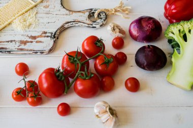 Domates, peynir, yeşil ve soğan taze vejetaryen yemek yemek. Sebze yemek yapmak için hazır. Ahşap kırsal masa ve malzemelerin üzerine açık renkli. Vejetaryen yiyecekler, kavram pişirme.
