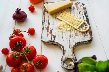 Domates, peynir, yeşil ve soğan taze vejetaryen yemek yemek. Sebze yemek yapmak için hazır. Ahşap kırsal masa ve malzemelerin üzerine açık renkli. Vejetaryen yiyecekler, kavram pişirme.