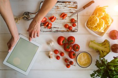 Üstten görünüm sağlıklı yemek pişirme, sos tarifi kullanarak bir dijital tablet evde yapımında bir kadından. Sebze malzemeler kesme. Görüntü elinde. Sağlıklı gıda. Sebze salatası. Evde yemek. Hazırlamak.
