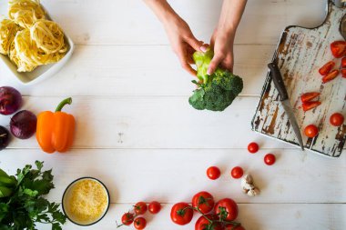 Üstten görünüm womam eller. Gıda arka plan. Gıda kavramı. Yemek pişirmek için çeşitli taze malzemeler. Mutfak masasında renkli sebze ile resmi. Dilimlenmiş sebze yemek yapmak için. Seçici odak.