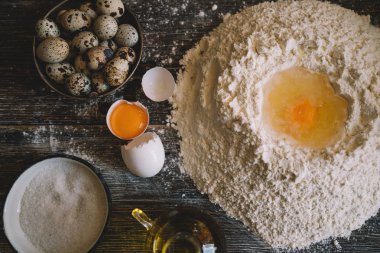 Yemek, yemek ve pişirme kavramı. Hamur un toz bir rustik ahşap zemin üzerine. Çiğ hamur pizza, malzemeler ve mutfak aksesuarları koyu ahşap arka plan üzerinde için.