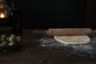 Mutfak masasının üzerinde oklava ile hamur. Pizza hamur ahşap bir oklava ile bir daire yayıyoruz. Yemek, yemek ve pişirme kavramı. Un, vintage ahşap masa üzerinde yumurta. Rustik arka plan kopya alanı ile.