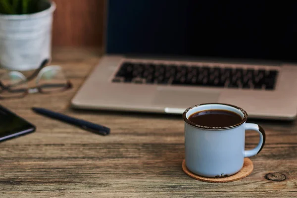 Vintage desk with laptop, eye glasses, smartphone, pen and a cup of coffee, top view. The blank notebook can be used to put some text or images. Business concept with copy space. Vintage style.