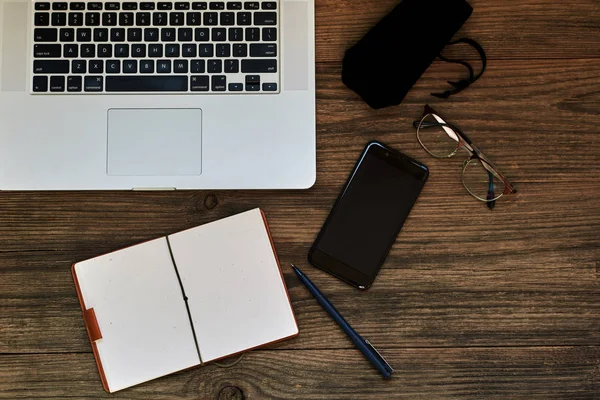 İş kavramı kopya alanı ile. Ofis resepsiyon masası. Çalışma alanı boş not defteri, dizüstü bilgisayar, gözlük smartphone ve kupa vintage ahşap masa üzerinde kahve. Vintage tarzı. 