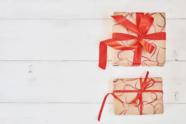 假日背景生态纸礼品盒与红色缎带在粉彩木制葡萄酒表 模拟礼品盒和装饰丝带和弓 顶部视图 设计背景 — 图库照片