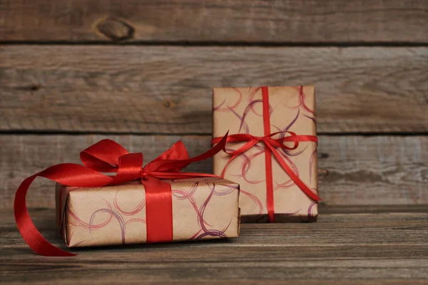 礼品盒包覆再生环保纸与红色缎带上的灰色木制葡萄酒表 模拟礼品盒和装饰丝带 设计背景 假日概念 复古风格 — 图库照片