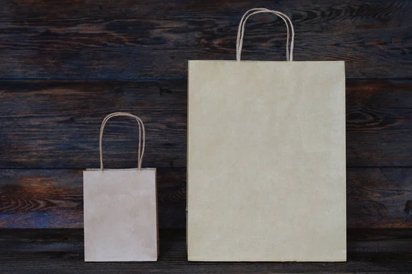 Mock-up of  brown paper package with handles, blank craft shopping bag with area for your logo or design, wooden board in the background, food delivery concept.