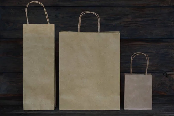 Sale, consumerism and advertisement concept -  blank  brown paper  bags on the vintage wooden board background. Paper bags with handles, blank craft shopping bag with area for your logo or design.