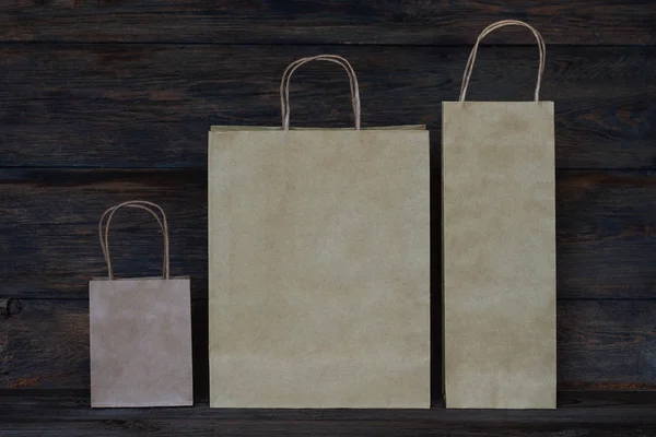 消費者と広告のコンセプト ヴィンテージの木製ボードの背景に空白の茶色の紙袋 ハンドル ロゴやデザインの領域に空白クラフト ショッピング バッグと紙袋 — ストック写真
